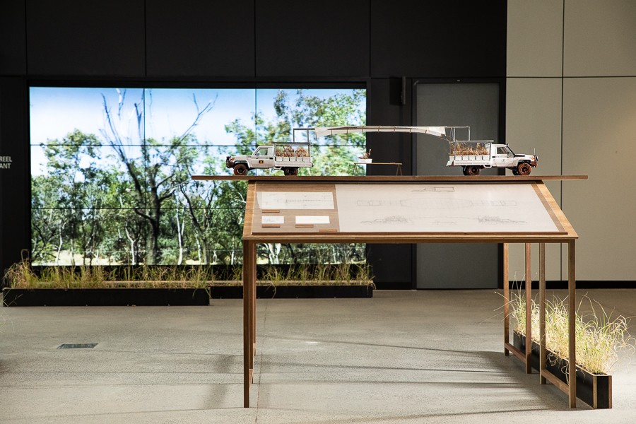 Two model trucks on table with grains in them in front of images on screen