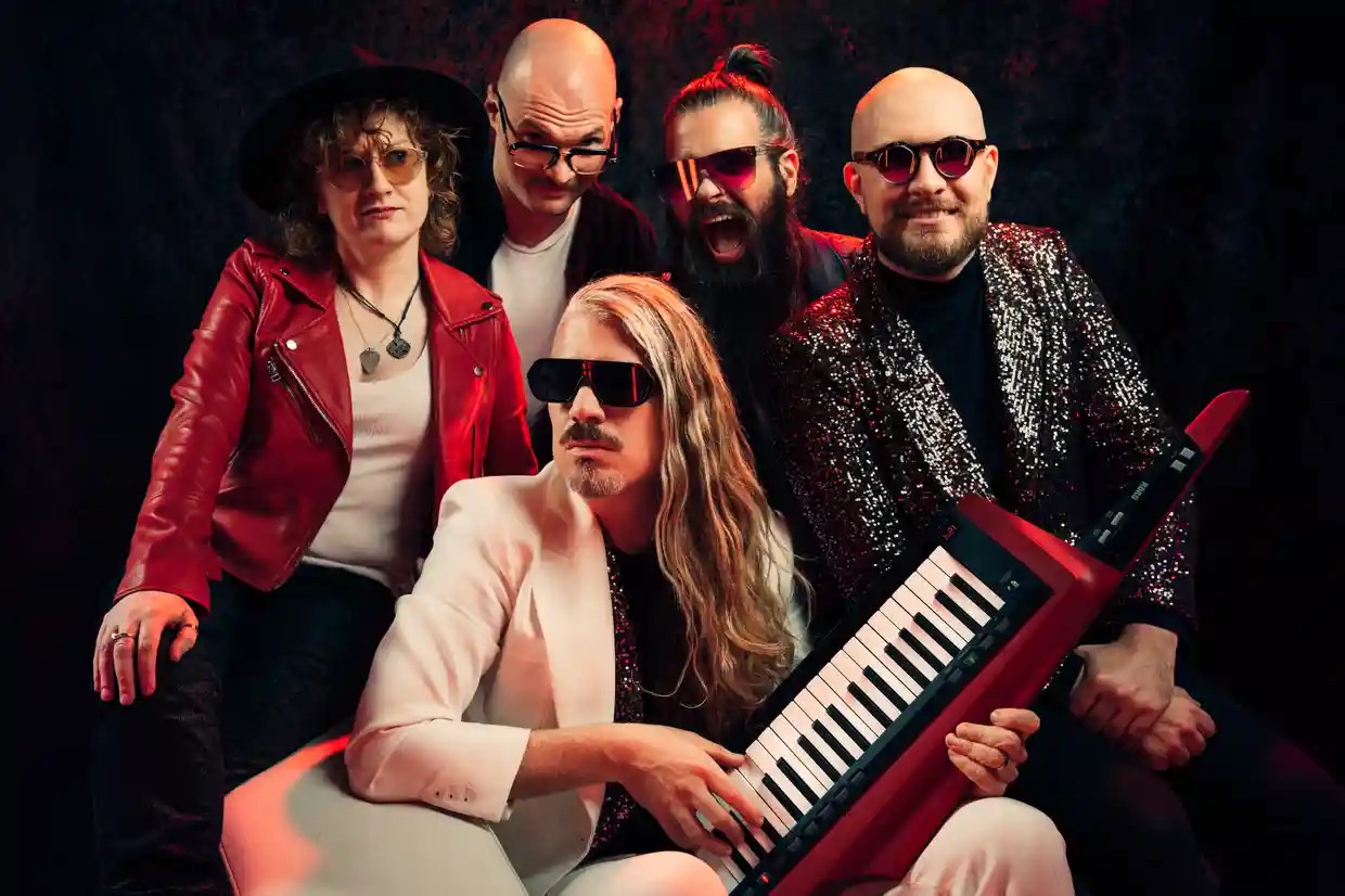 five members of a band pose for a photo shoot in a studio