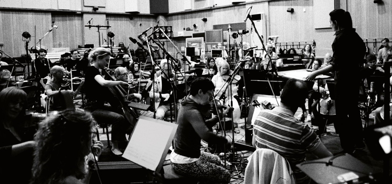 a black and white photo of an orchestra packed tightly in chairs in the small Abbey Road Studios with Natalie Murray Beale