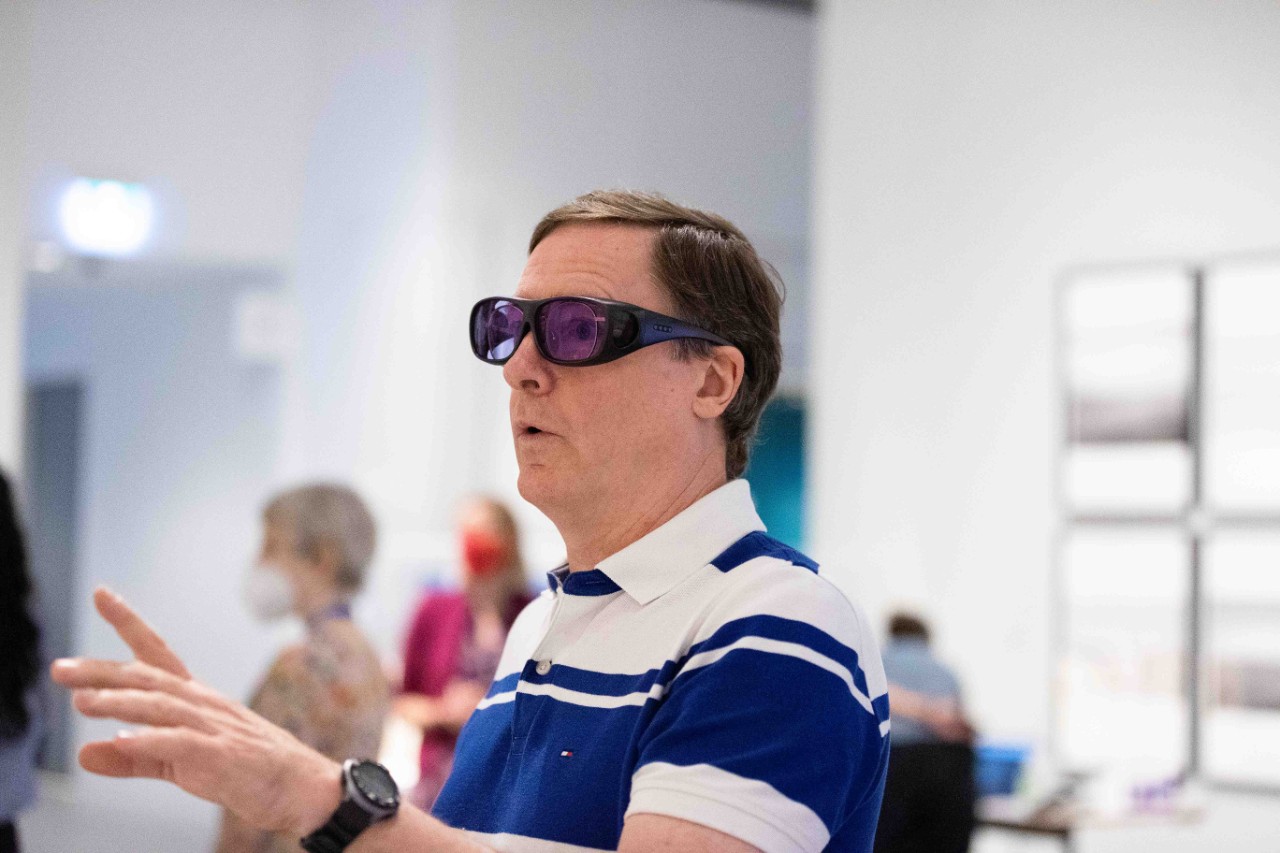 photo of a man with glasses on looking amazed while he looks at a painting