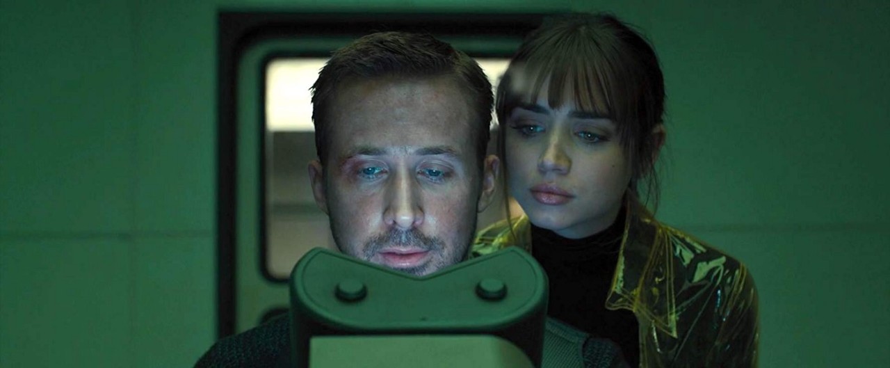 A man and a woman look into a microscope