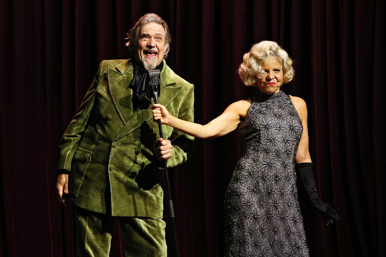 photo of a man and a woman wearing a sparkly dress on stage looking happy