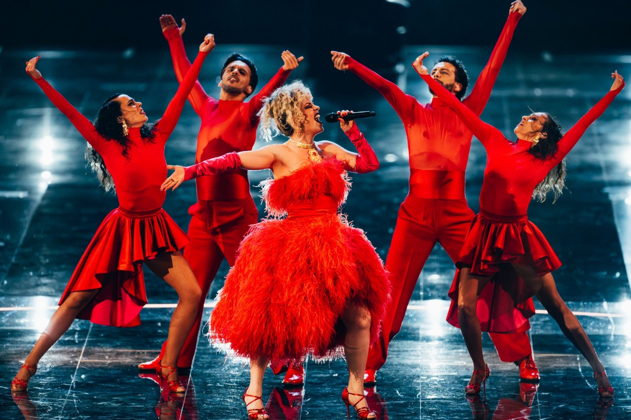 photo of a female singer in a huge red dress singing on stage