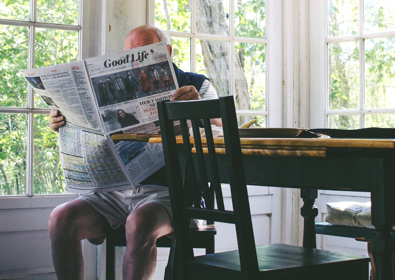 Elderly man reading newspaper