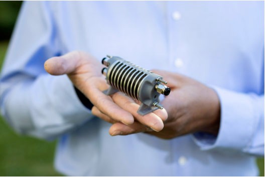 Professor Kondo-Francois Aguey-Zinsou holding a mechanic piece of equipment in his hand.