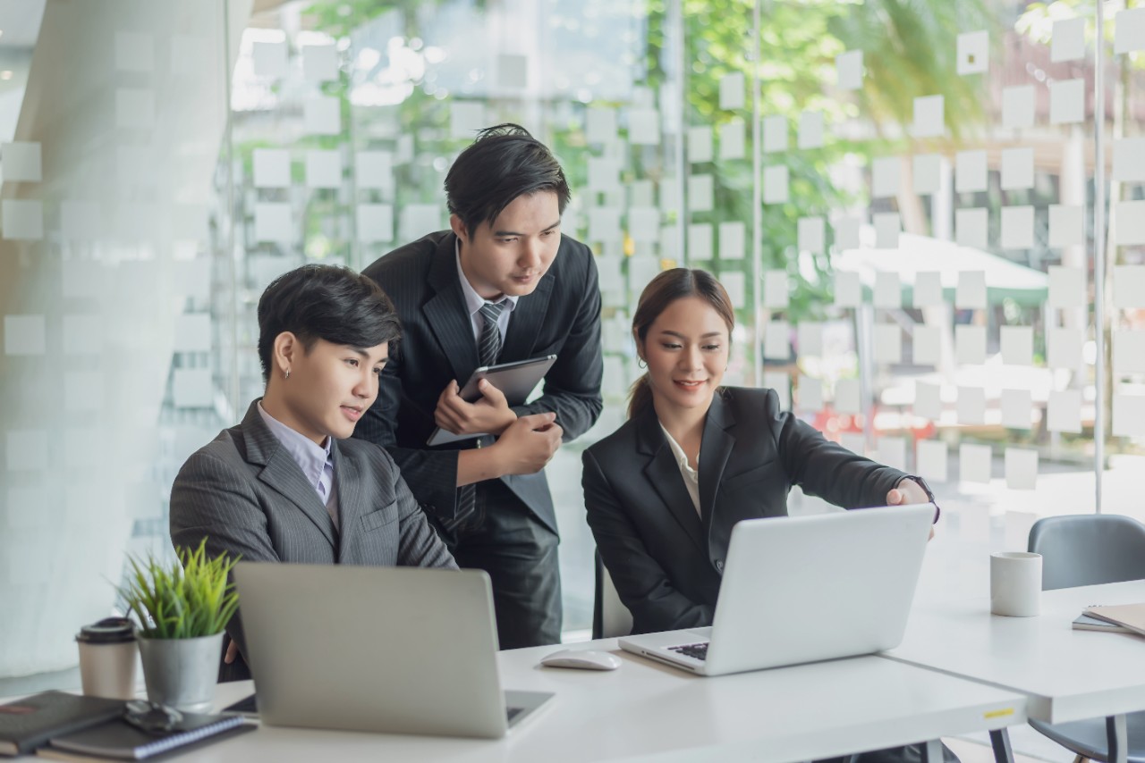 photo of three asian business people looking at a laptop together