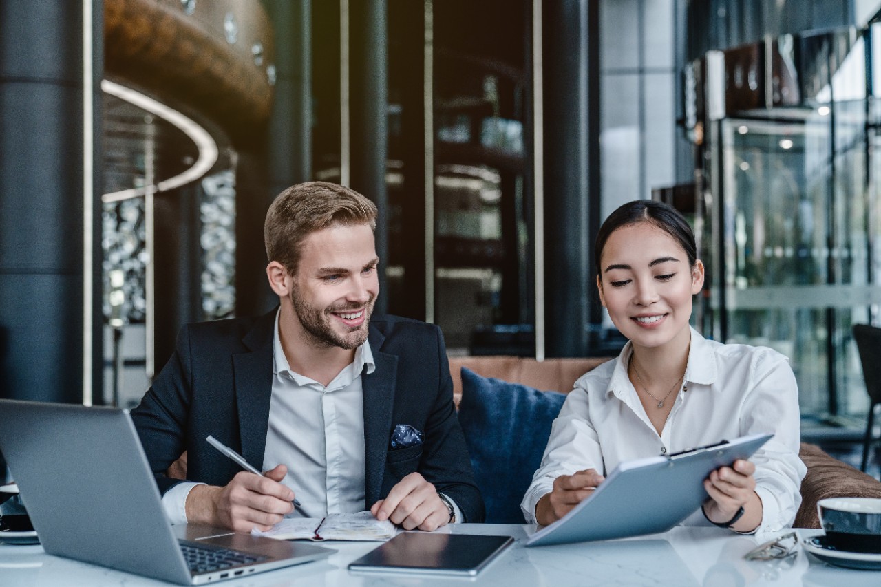photo of two young business people, the man has blonde hair and a beard and the woman is of Asian appearance