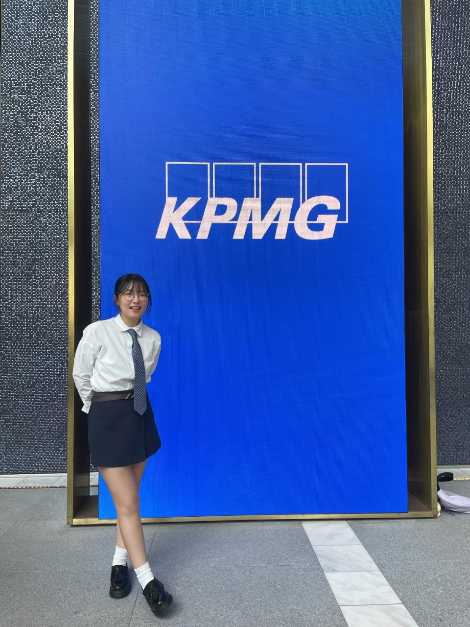 Student stook in front of KPMG banner