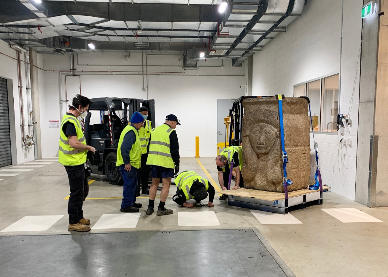 Workmen with sculpture in loading dock