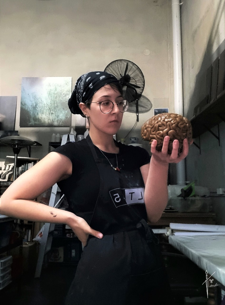 Dan Marie De Nardis, holding and looking at a sculpture of a brain