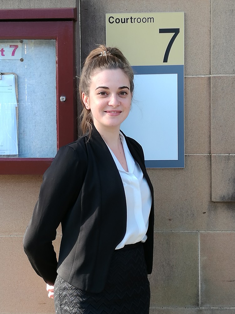 Tallulah Bur stands next to a sign displaying 'Courtroom 7'