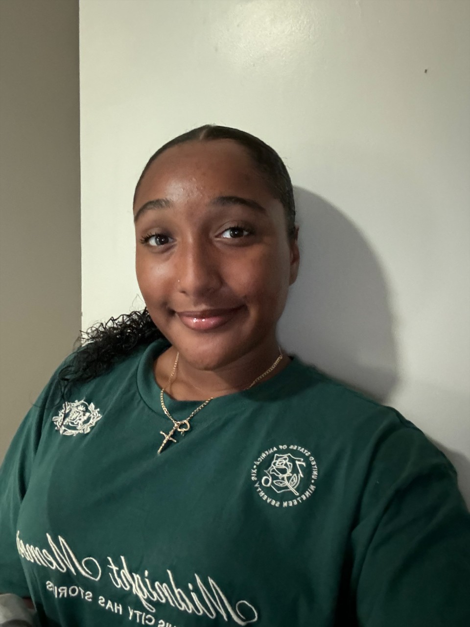 A young Yuin woman with long, dark hair in a low ponytail and is wearing a green jersey. 