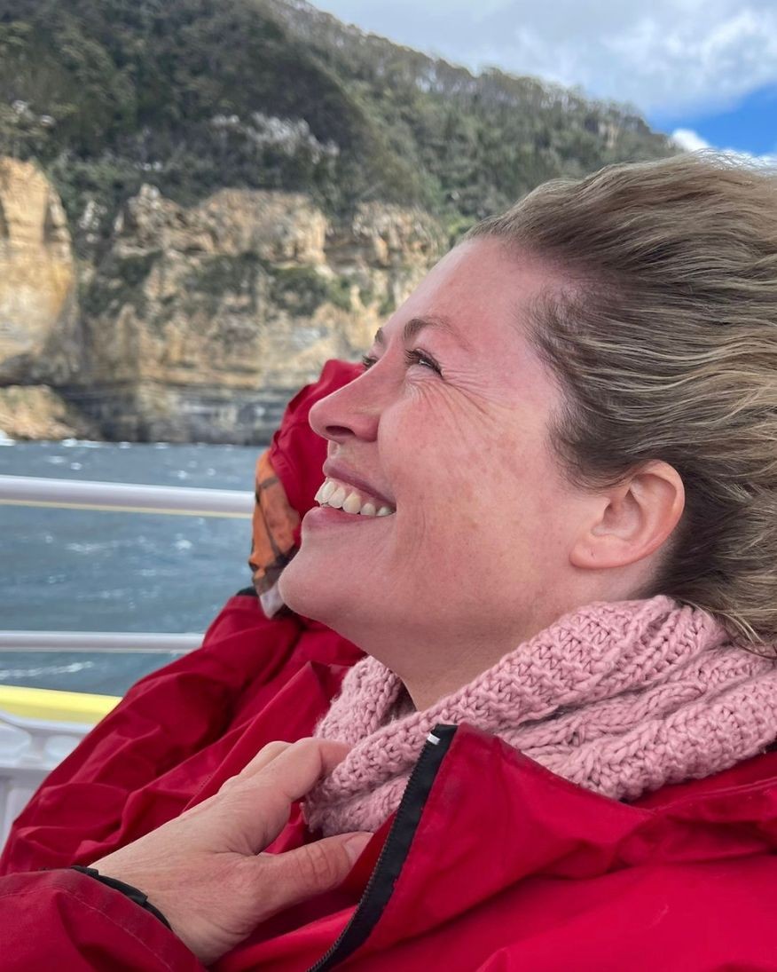 A side profile image of Natali on a boat with a red jacket and the wind blowing her hair