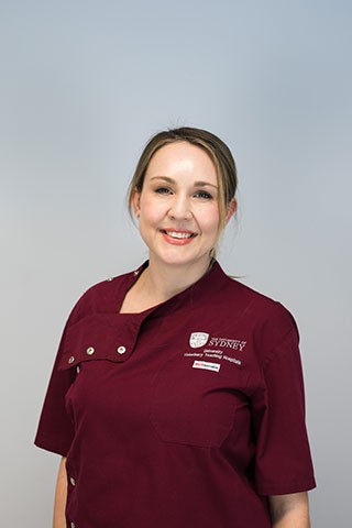 Image of Dr Cicilia Muller in a red scrubs jacket with University logo.