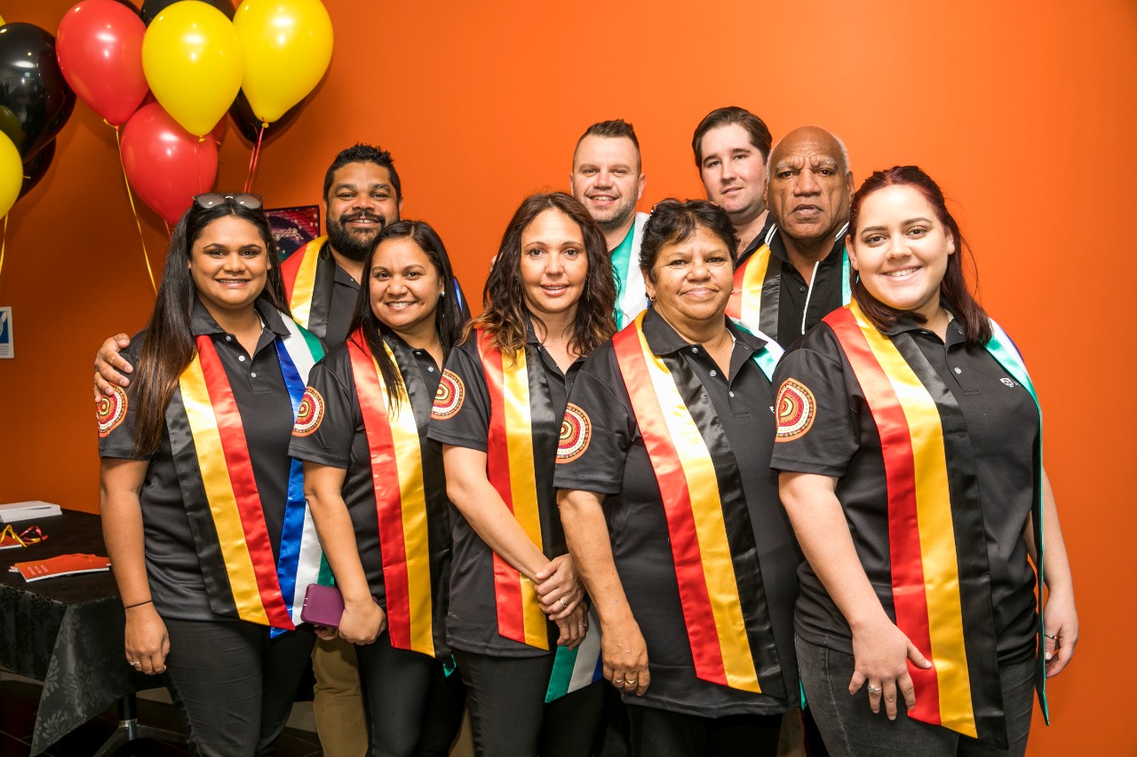 A photo of a group of Aboriginal students wearing red, yellow and black sashes.