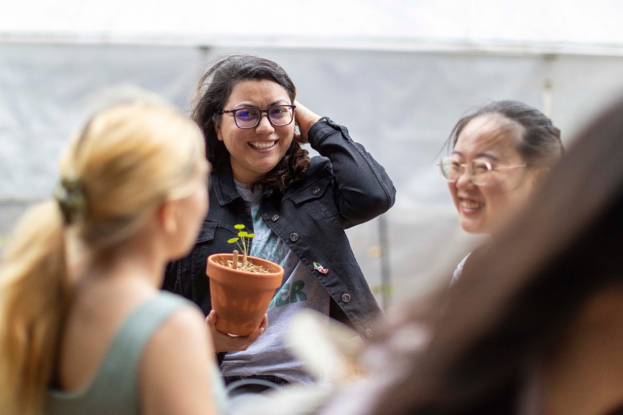 A group of gardening workshop attendees gather together, talking and smiling.