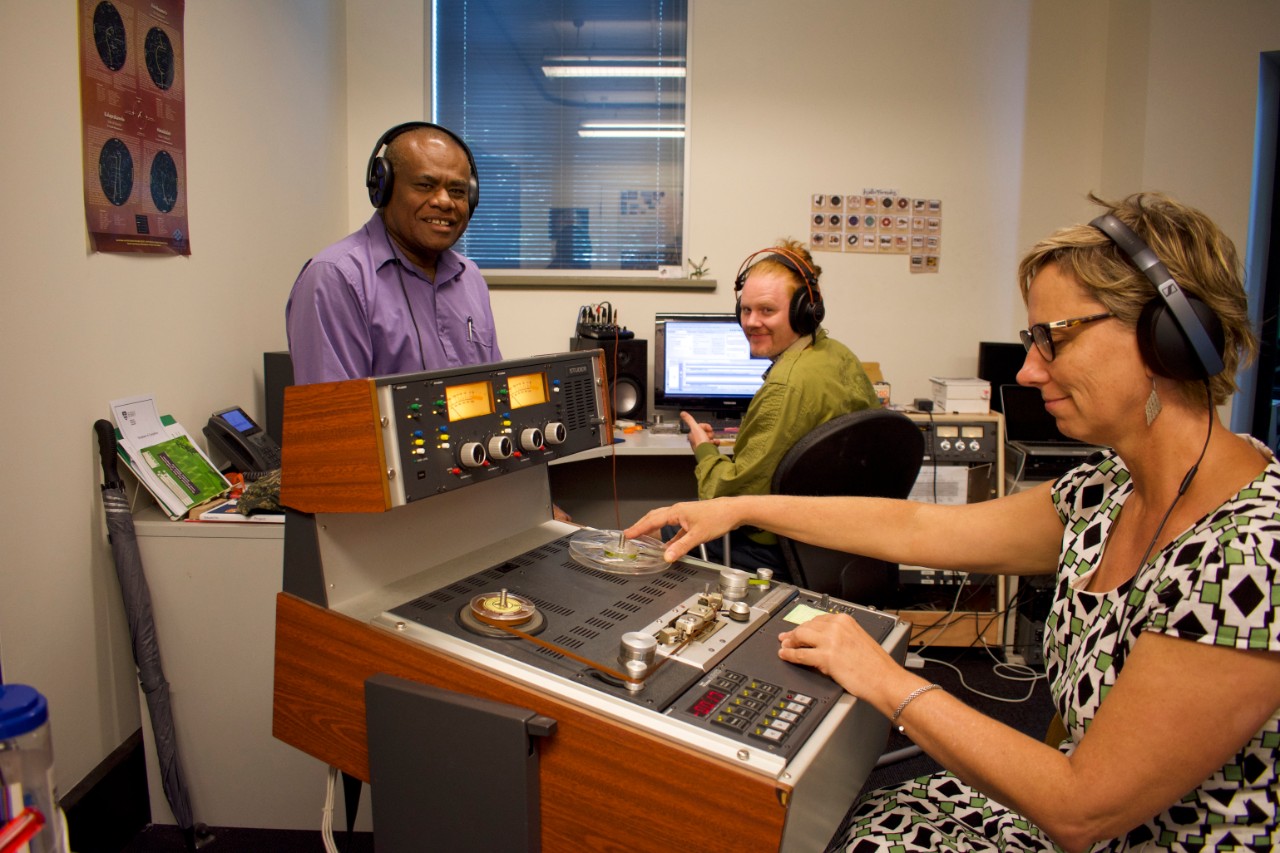 three researchers in a lab caring for old tapes on a tape machine