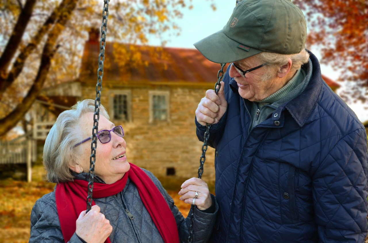 A photo of an older couple, she's on a swing.