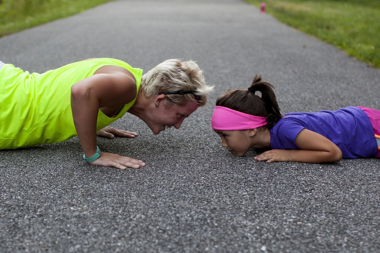 Older lady with girl doing push ups outside