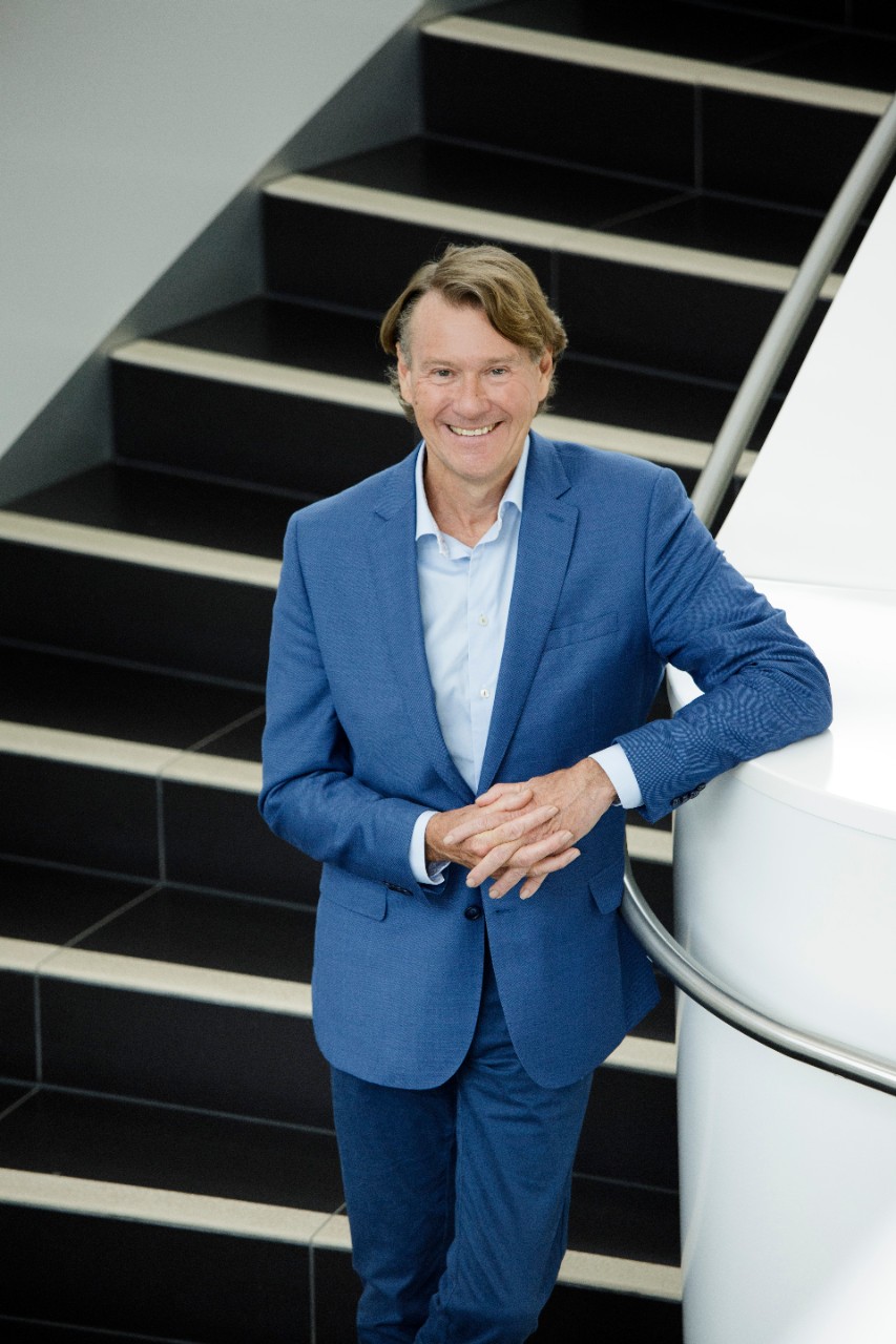 Professor Stephen Simpson AC staring up at the camera in a blue suit, smiling.