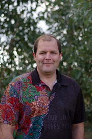 John Gilroy pictured outdoors in a colourful shirt and with trees in the background. 