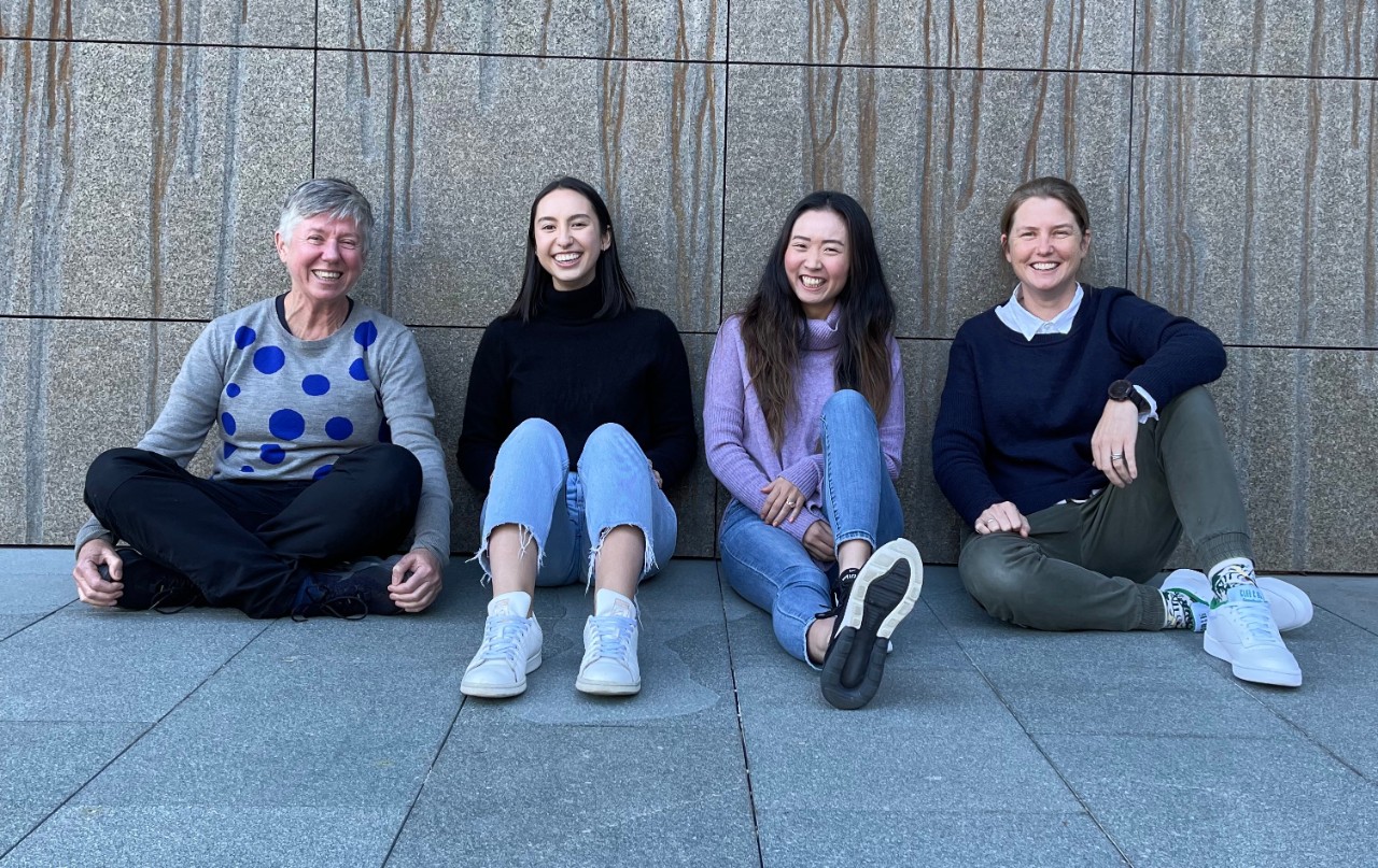 four women sitting on the ground posing for a photo