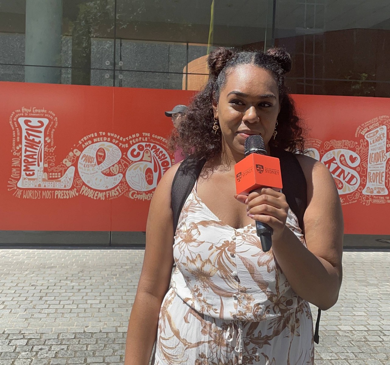 Second year student Patriciea standing outside Carslaw building with a microphone