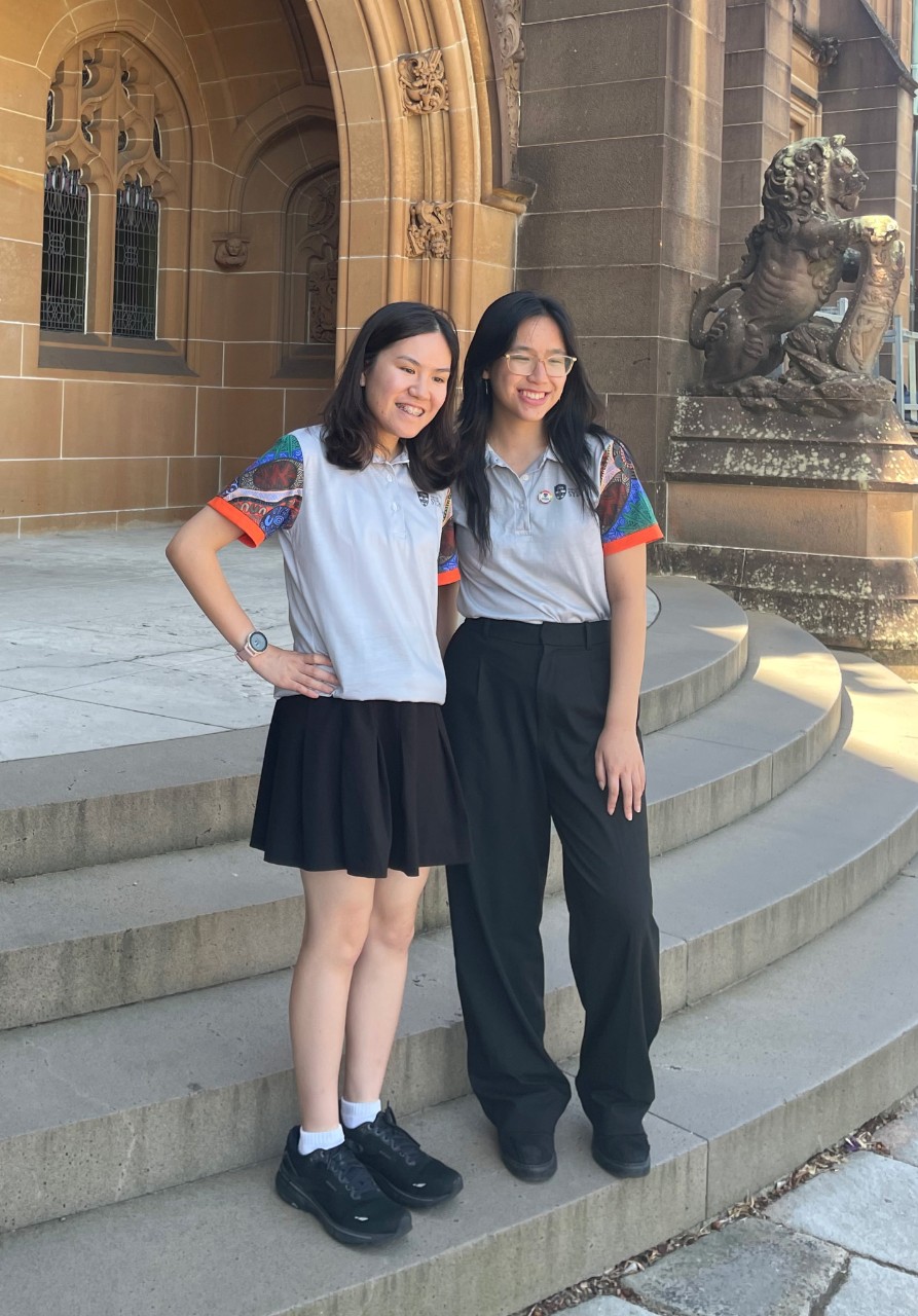 Two female students standing on the steps of side entrance to Quadrangle building