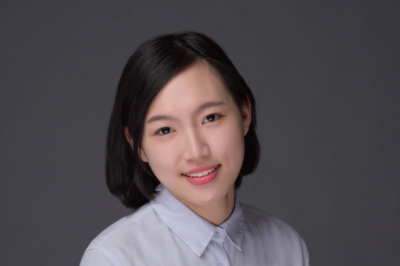 Portrait of a woman in a collared shirt against a dark background