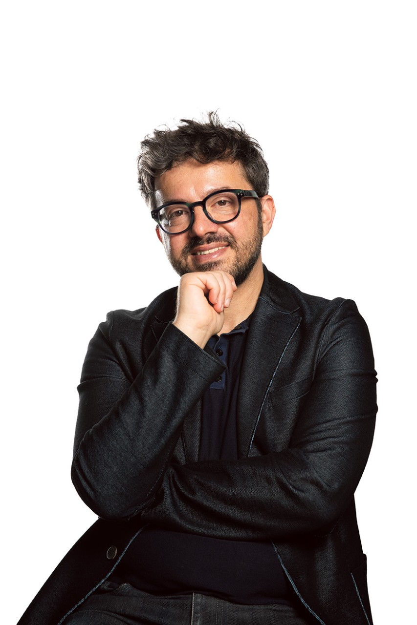 Yane in all black and smiling, hand on his chin