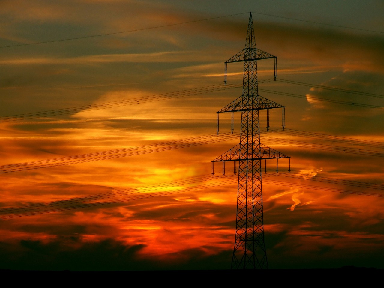 Power poles seen at sunset, representing the energy market.