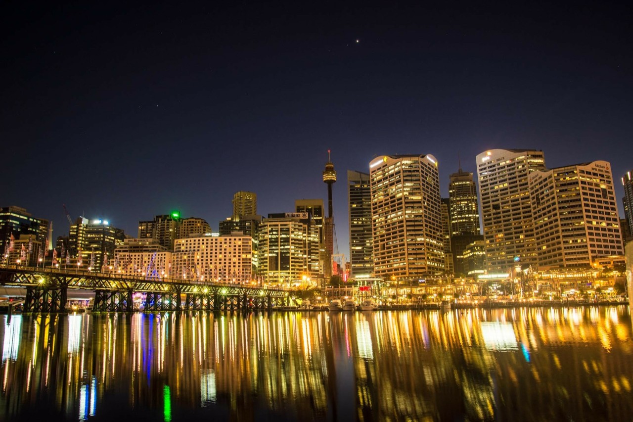 Sydney Harbour at night, lights reflected in the water. 