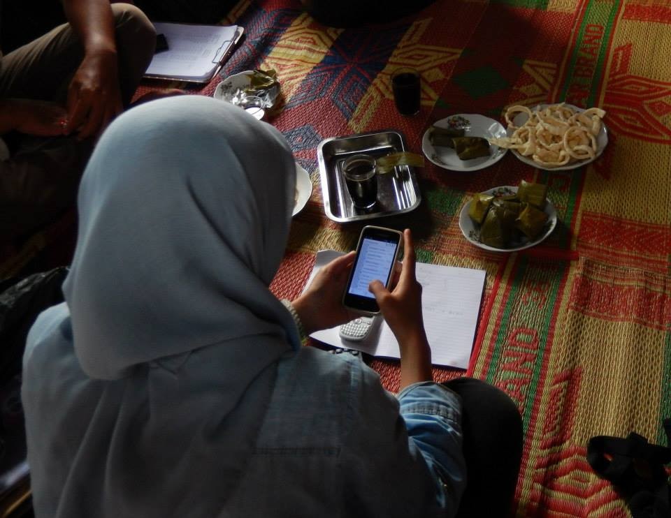 A research assistant using one of her phones during a break in interview with a farmer in his house in Sumatra. Photo from a survey supervised by Ayu Pratiwi. Photo: Petr Matous.
