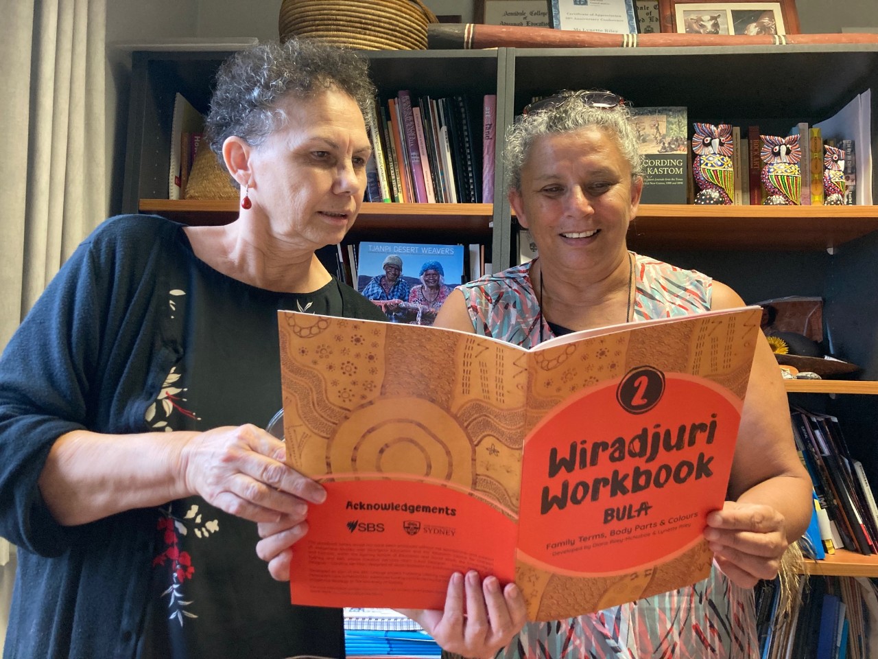 L-R: Associate Professor Lynette Riley and her sister, Diane McNaboe reading from one of their workbooks. 