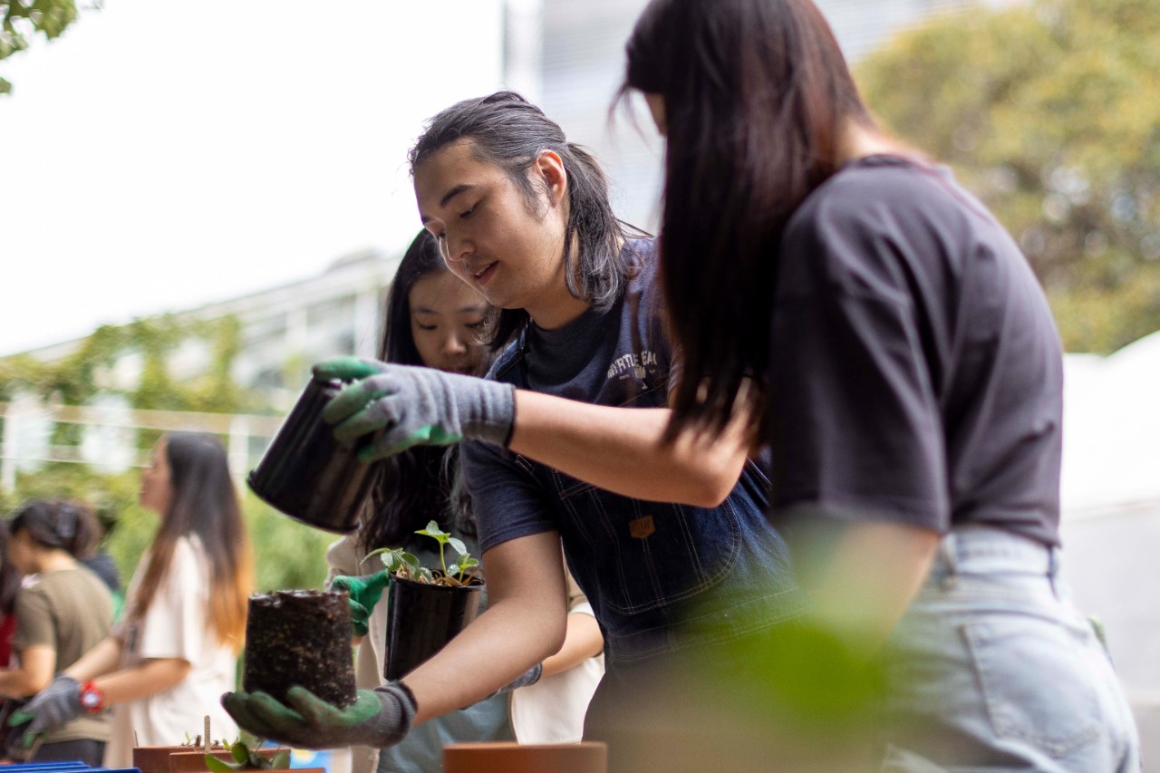 Photograph of Marcel at the Balcony Gardening Workshop, helping a student pot a plant.